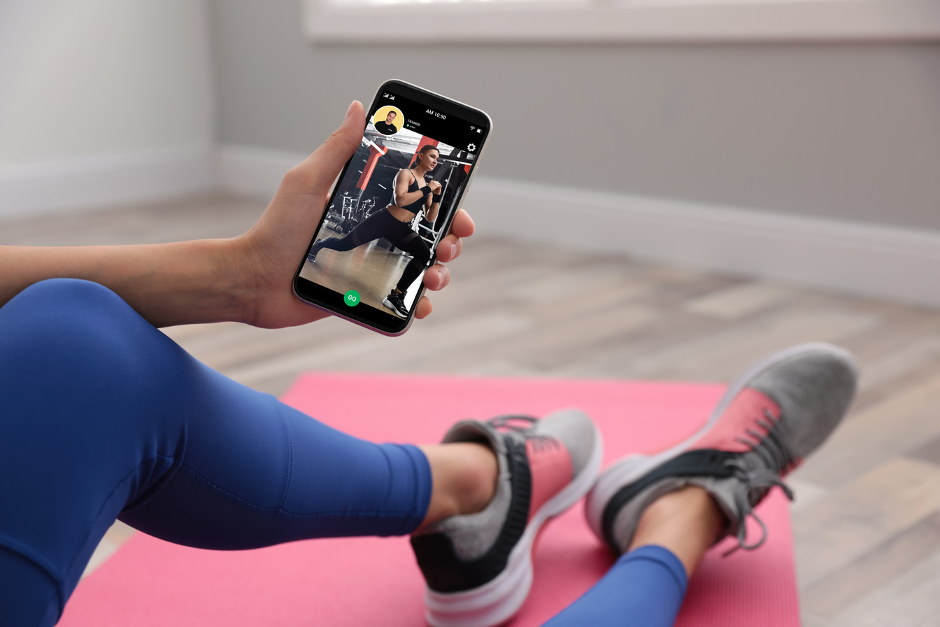 Young Woman Using Fitness App on Smartphone Indoors, Closeup